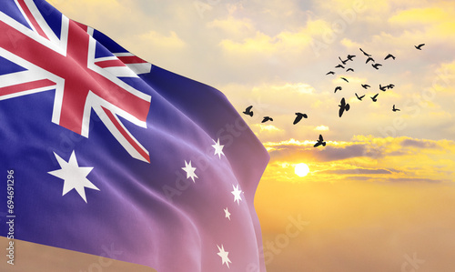 Waving flag of Australia against the background of a sunset or sunrise. Australia flag for Independence Day. The symbol of the state on wavy fabric. photo
