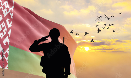 Silhouette of a soldier with the Belarus flag stands against the background of a sunset or sunrise. Concept of national holidays. Commemoration Day.