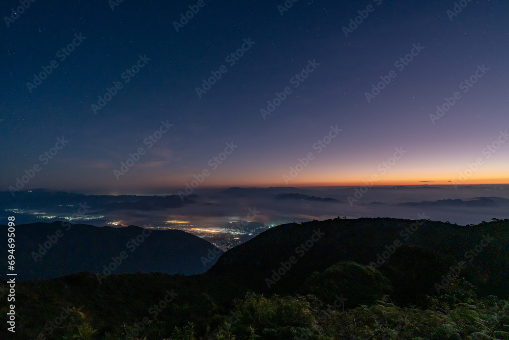 Obraz premium Early morning night sky from the top of Doi Luang Chiang Dao in Chiang Mai, Thailand overlooking a glowing town lights and beautiful dark blue sky