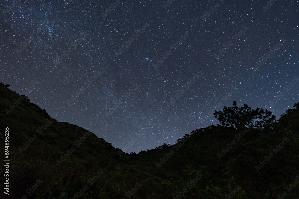 Night sky full of stars and tail of milky way from the top of Doi Luang Chiang Dao in Chiang Mai, Thailand with silhouette of mountains top in the foreground