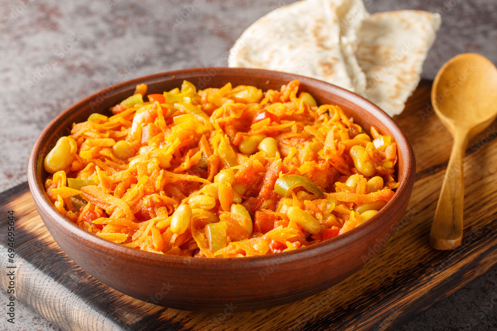Fototapeta premium Chakalaka is a staple south African dish made from beans, fresh veggies, onions, pepper, and tomatoes closeup on the bowl on the table. Horizontal
