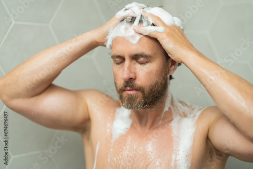 Hispanic man washing hair in bathroom. Guy bathing shower head in bathtub. Male face in shower. Man taking shower in bathroom. Guy showering. Bathroom concept. Man is under water drops in bathroom.