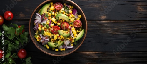 Mexican corn salad with avocado, red onion, and tomatoes, presented on a black bowl on a dark wooden table, high-angle view, minimalistic style.