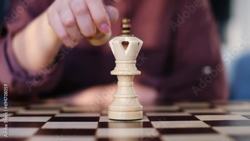 A woman's hand thoughtfully replaces a queen with a pawn on the chessboard, a deliberate strategy that evokes the nuanced tactics of understatement and patience. photo