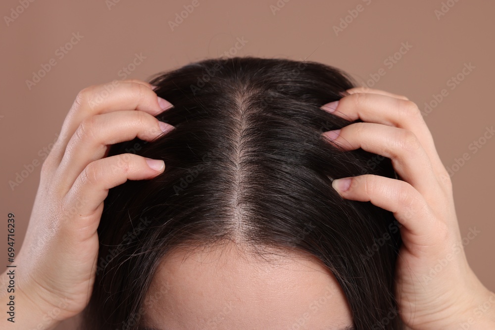 Woman examining her hair and scalp on beige background, closeup Woman examining her hair and scalp on beige background, closeup