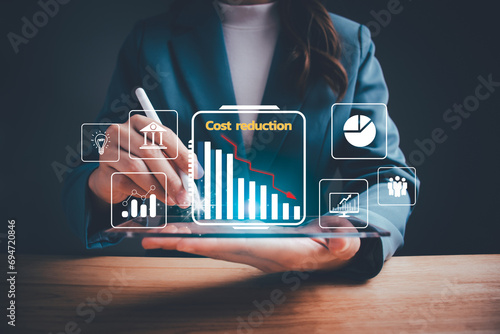 Businesswoman pointing down arrow of the graph with cost reduction business finance on virtual screen. Business, technology, cost management, cut budget, cost reduction concept. photo
