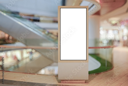 Vertical OOH out of home poster display in retail environment. Advertising digital screen in shopping mall. Out of focus bokeh effect in background