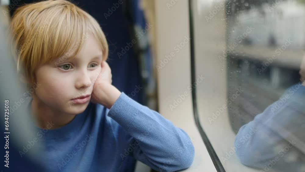 Cute preteen boy is traveling in a subway train carriage or by railroad while it rain outside. Portrait of child passenger. Stock ビデオ | Adobe Stock