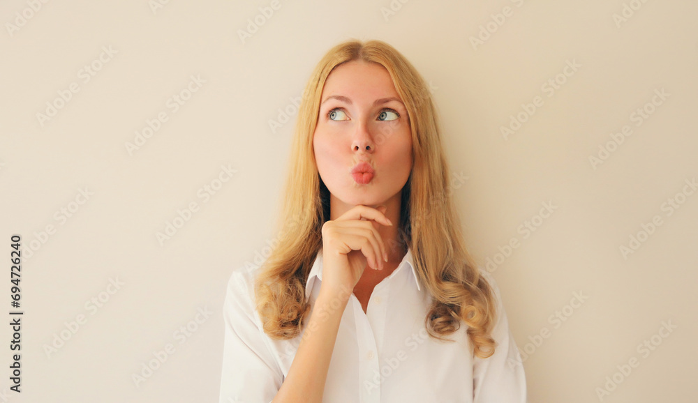 Pensive caucasian young woman employee thinks looking up on studio background Pensive caucasian young woman employee thinks looking up on studio background