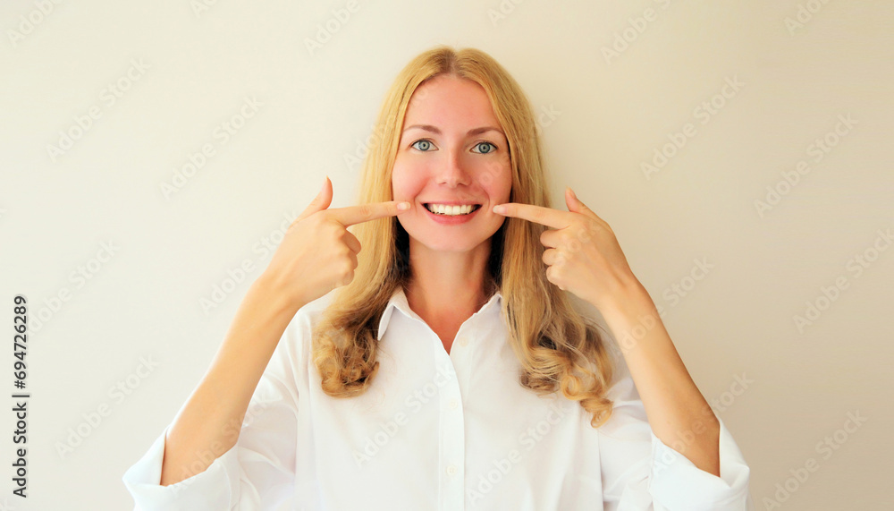 Portrait of happy smiling young woman points with fingers to her white clean teeth at home Portrait of happy smiling young woman points with fingers to her white clean teeth at home