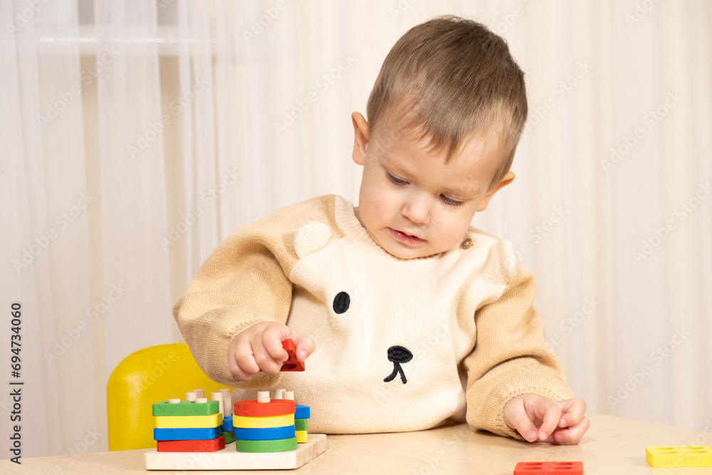A two-year-old boy plays with wooden toys to develop logic and motor skills A two-year-old boy plays with wooden toys to develop logic and motor skills
