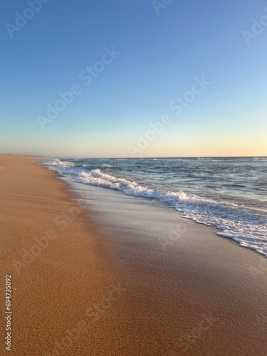 Sandy ocean shoreline, empty beach, warm evening light