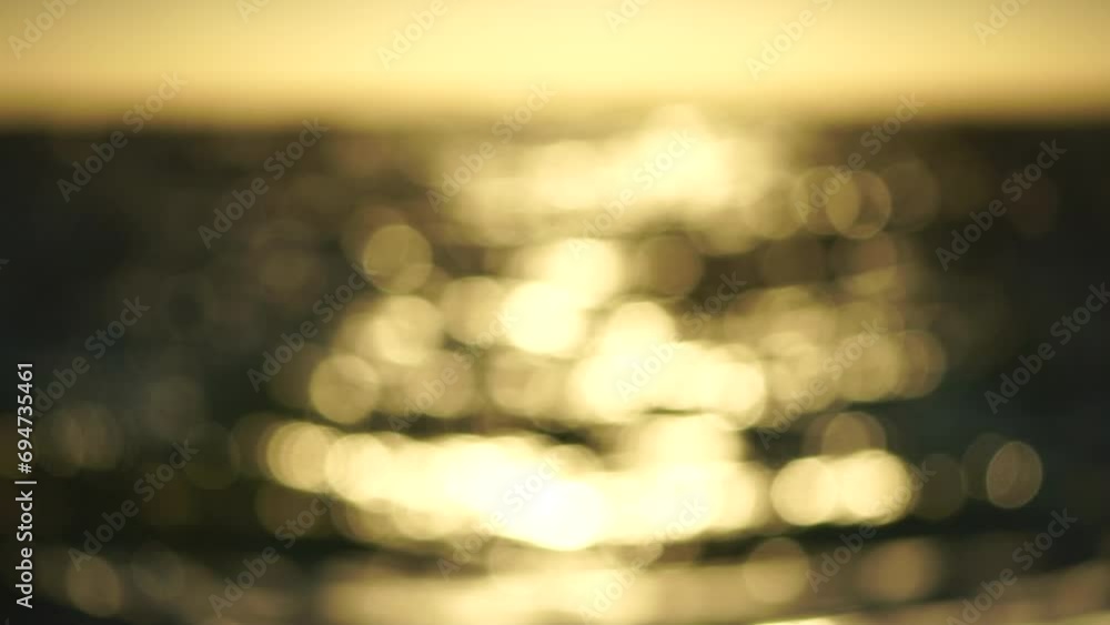 Blurred golden sea at sunset. The sun reflects and sparkles on the waves with bokeh, illuminating the golden sea. Holiday recreation concept. Abstract nautical summer ocean sunset nature background. Blurred golden sea at sunset. The sun reflects and sparkles on the waves with bokeh, illuminating the golden sea. Holiday recreation concept. Abstract nautical summer ocean sunset nature background.