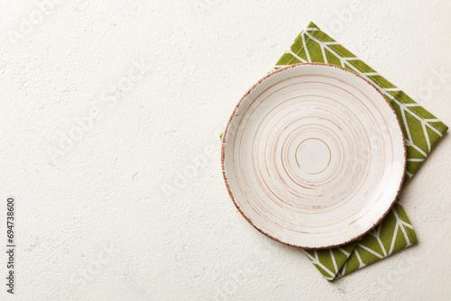 Top view on colored background empty round white plate on tablecloth for food. Empty dish on napkin with space for your design photo