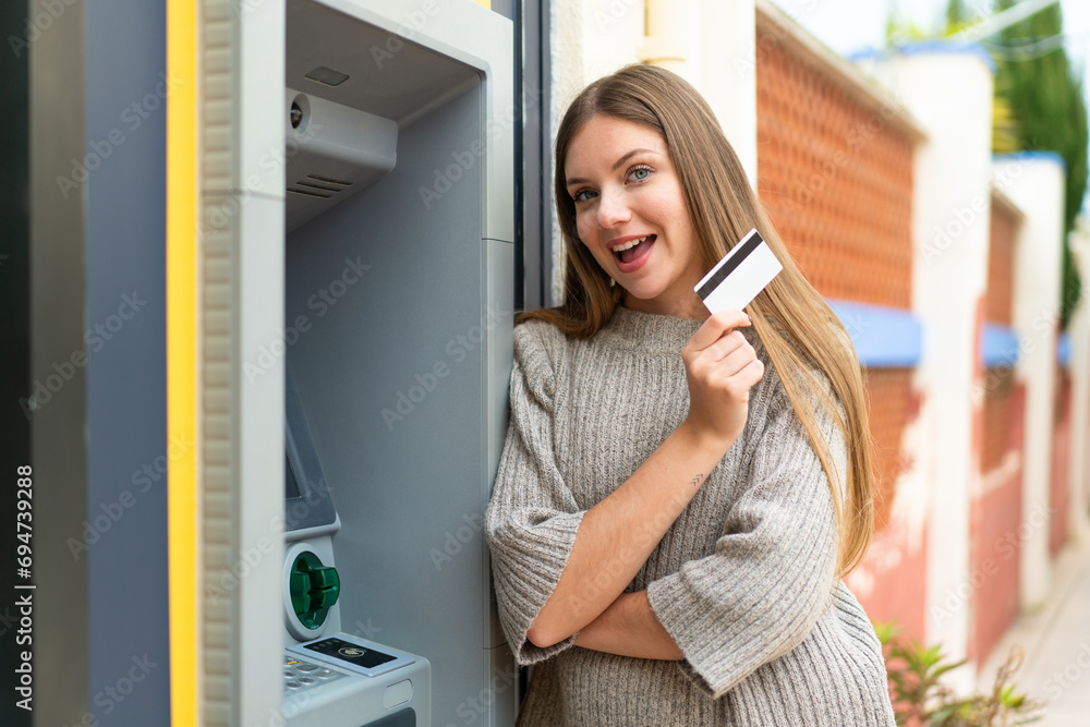 Young pretty blonde woman using an ATM