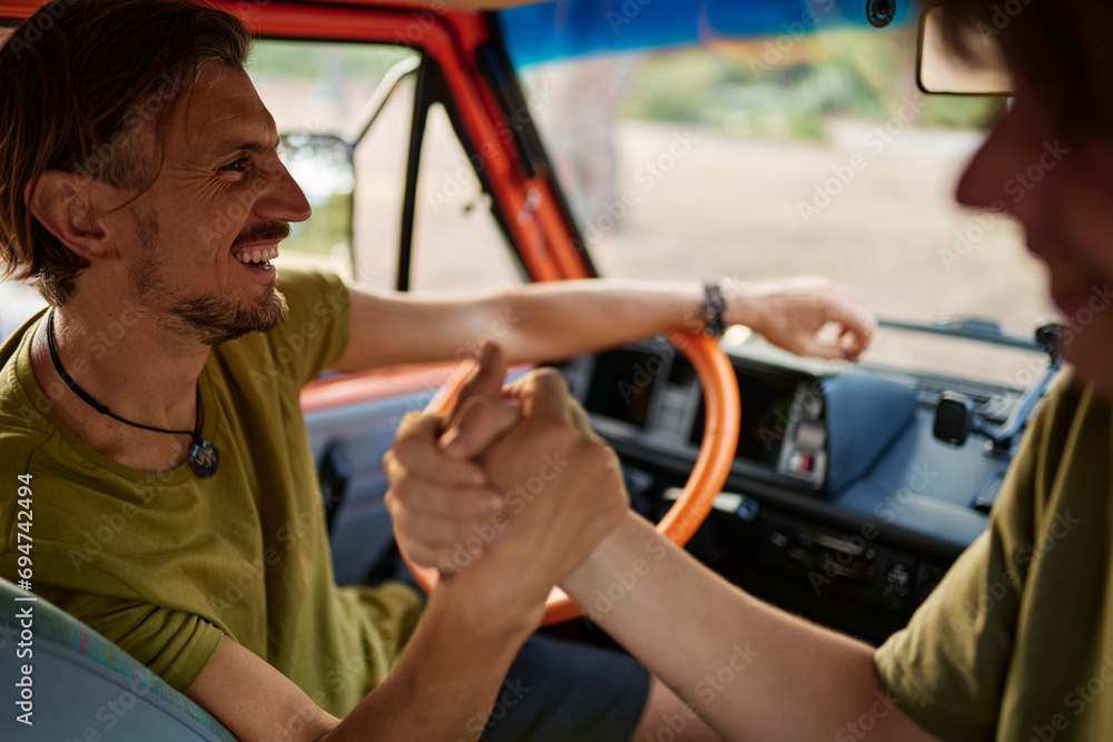 Happy father arm wrestling with son sitting in caravan Happy father arm wrestling with son sitting in caravan
