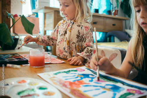 Girls drawing with paintbrushes and watercolors at home photo