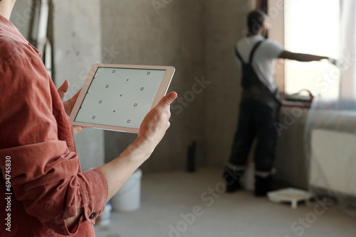 Engineer holding tablet PC with coworker in background at construction site photo
