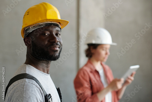 Construction worker wearing hardhat with engineer in background photo