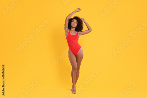 Beautiful woman in bright one-piece summer swimsuit on yellow background photo