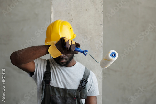 Tired construction worker wiping sweat at site photo