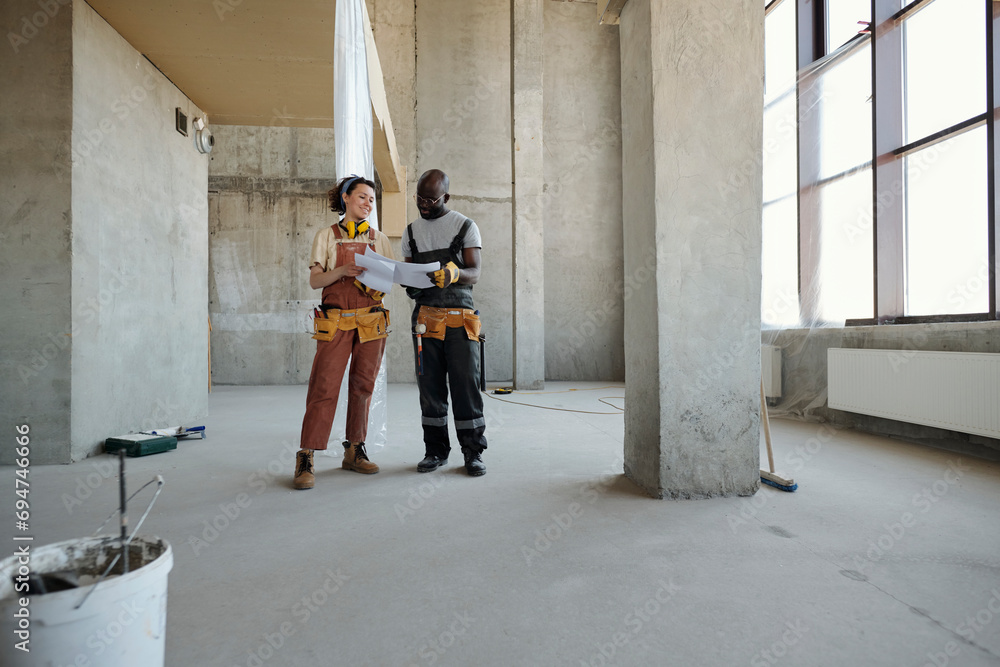 Engineer holding blueprint and planning with coworker at construction site Engineer holding blueprint and planning with coworker at construction site