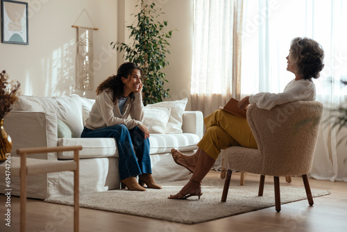 Smiling woman having consultation with psychologist in living room at home photo