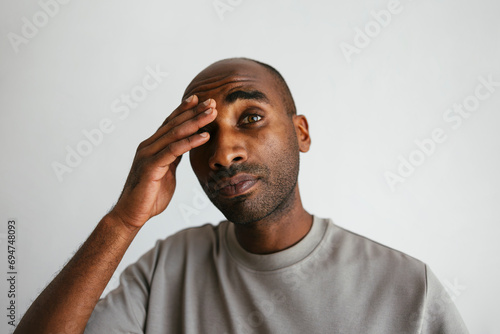 Man with head in hand against white background photo
