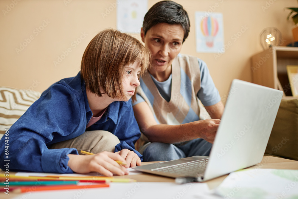 © Westend61 - Mother explaining lesson on laptop to daughter with Down syndrome at home