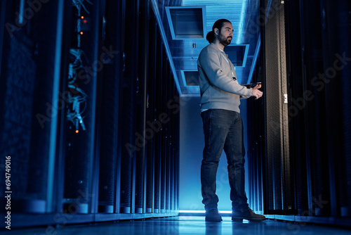 Young IT engineer examining supercomputer equipment in server room