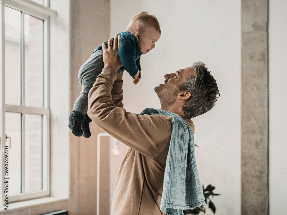 © Westend61 - Happy mature man playing with son at home