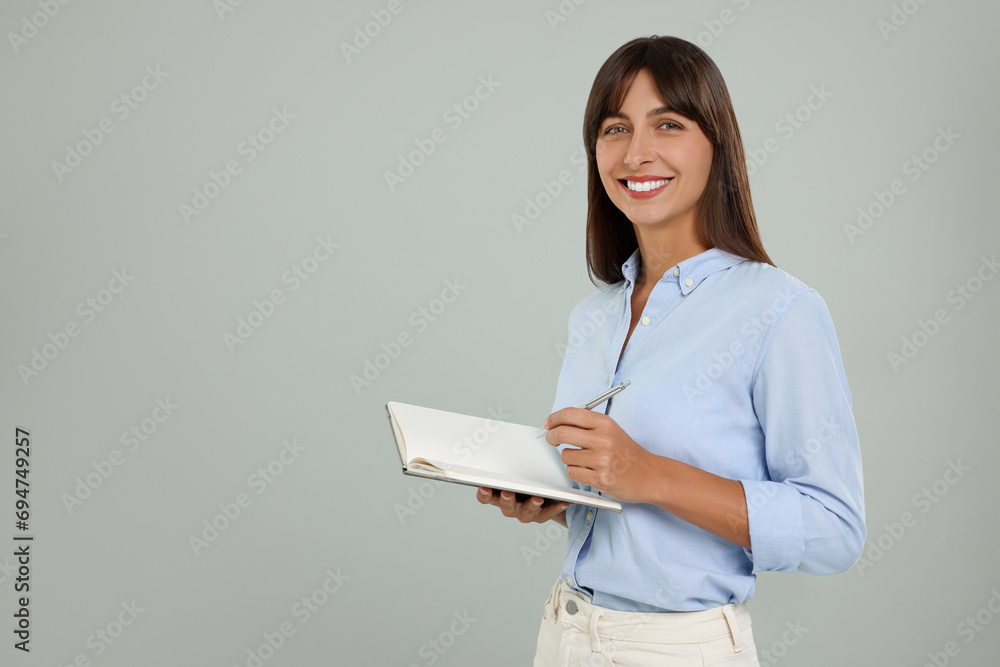Happy secretary with notebook and pen on light grey background. Space for text Happy secretary with notebook and pen on light grey background. Space for text
