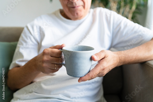 Senior man holding coffee cup in living room at home photo