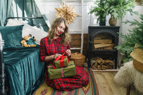 Happy woman opening Christmas presents at home photo