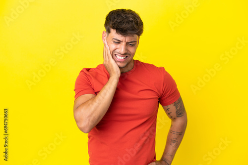 Young caucasian handsome man isolated on yellow background with toothache