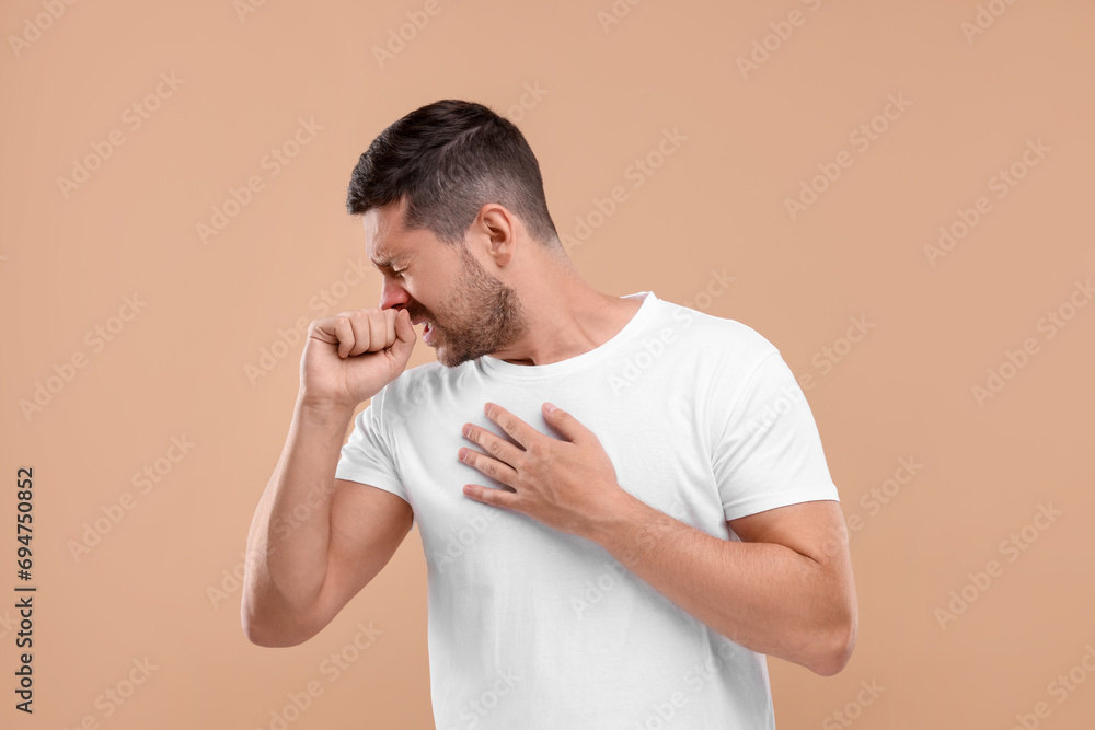 Allergy symptom. Man sneezing on light brown background Allergy symptom. Man sneezing on light brown background