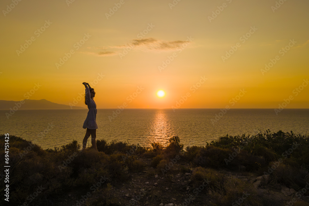 Woman in dress stand on seacoast during sunset at seascape. concept of healthy lifestyle and love of life
