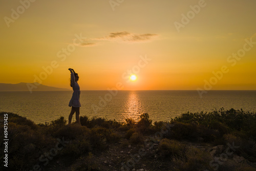 Woman in dress stand on seacoast during sunset at seascape. concept of healthy lifestyle and love of life