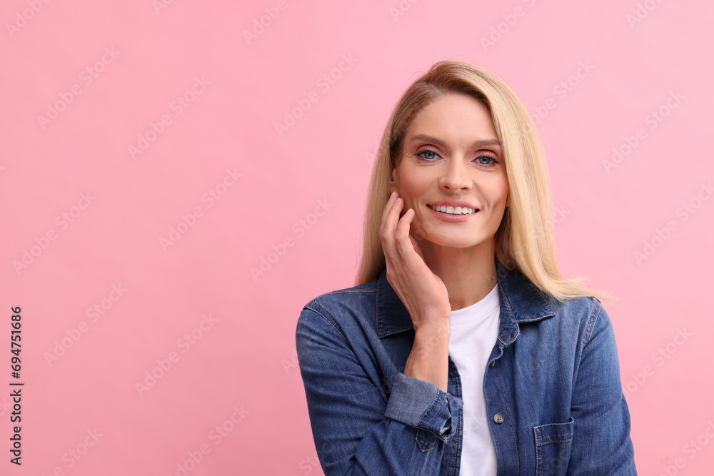 Portrait of smiling middle aged woman with blonde hair on pink background. Space for text Portrait of smiling middle aged woman with blonde hair on pink background. Space for text