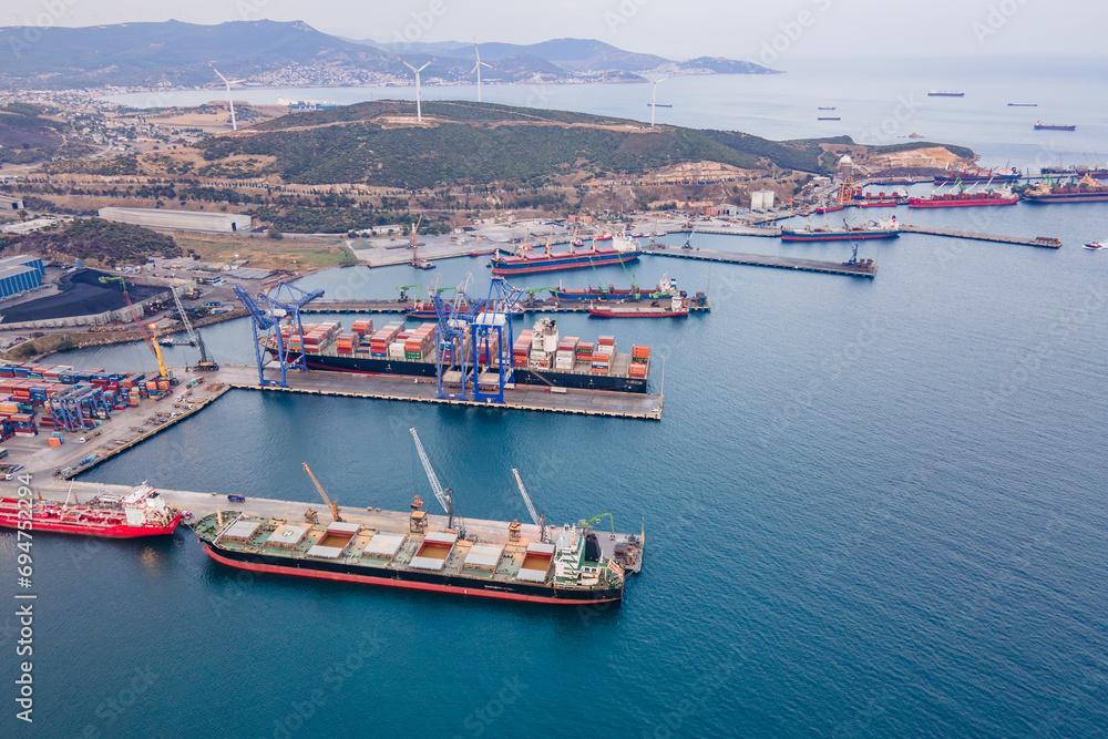 Cargo vessels uploading at freight cargo port terminal. Aerial view