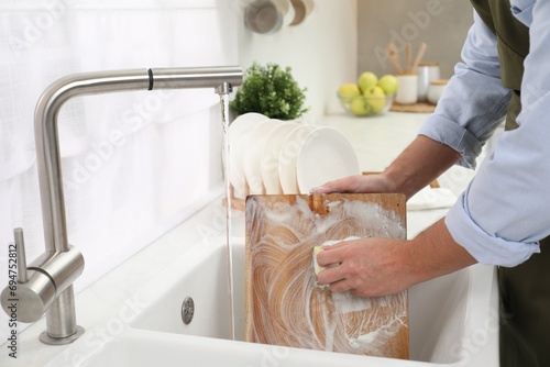 Foto Man washing wooden cutting board in kitchen sink, closeup