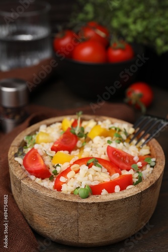 Cooked bulgur with vegetables in bowl on wooden table © New Africa