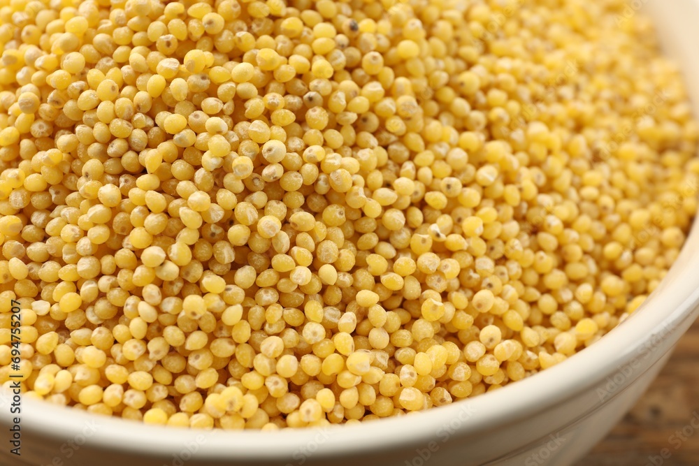 Millet groats in bowl on table, closeup Millet groats in bowl on table, closeup