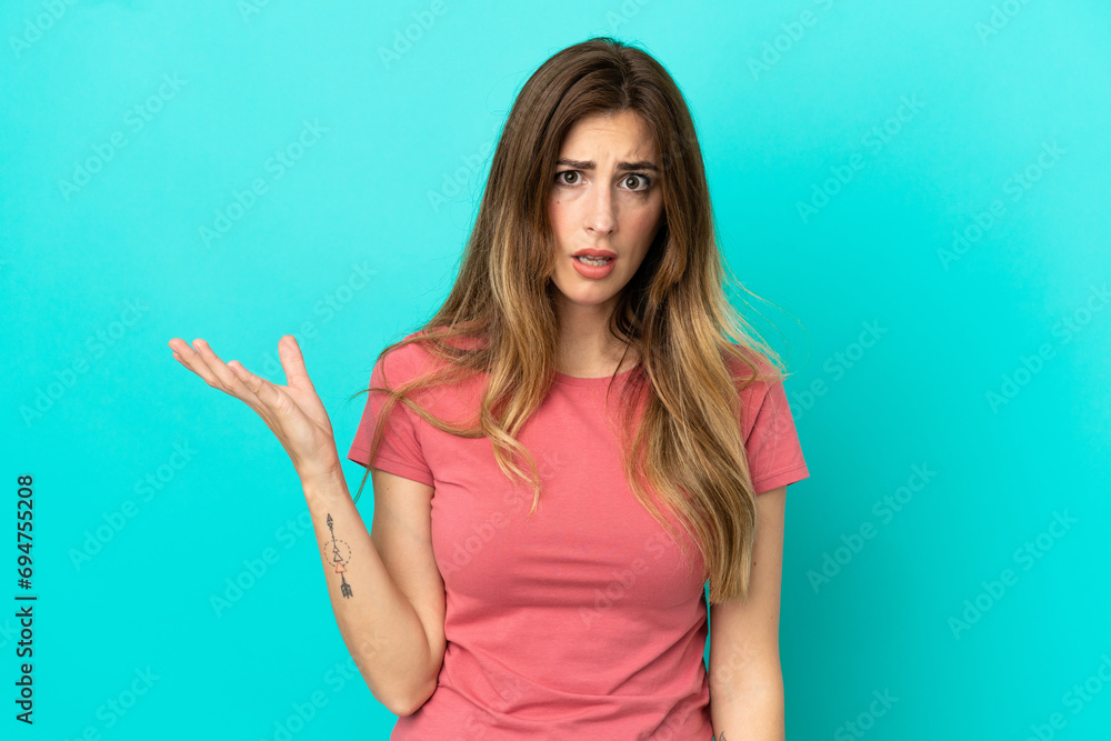 Fototapeta premium Young caucasian woman isolated on blue background making doubts gesture