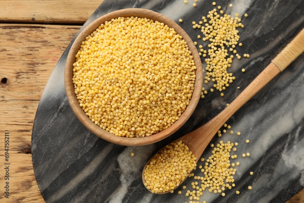 Millet groats in bowl and spoon on wooden table, flat lay Millet groats in bowl and spoon on wooden table, flat lay
