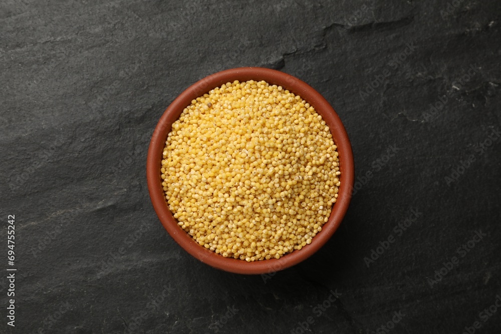 Millet groats in bowl on black table, top view Millet groats in bowl on black table, top view