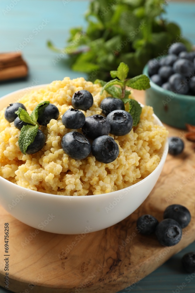 Tasty millet porridge with blueberries and mint in bowl on wooden table, closeup Tasty millet porridge with blueberries and mint in bowl on wooden table, closeup