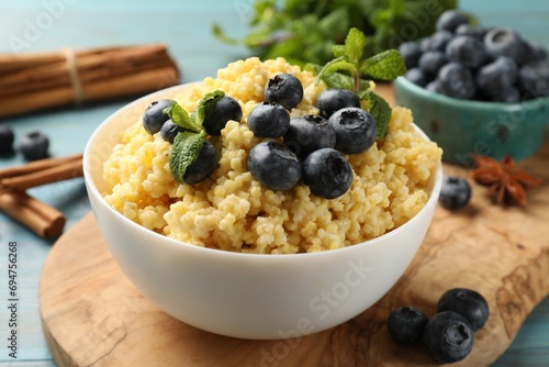 Tableau sur toile Tasty millet porridge with blueberries and mint in bowl on light blue wooden tab