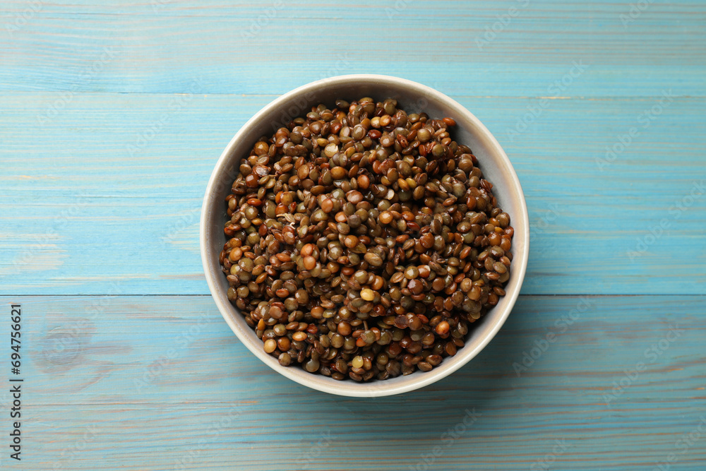 Delicious lentils in bowl on light blue wooden table, top view Delicious lentils in bowl on light blue wooden table, top view