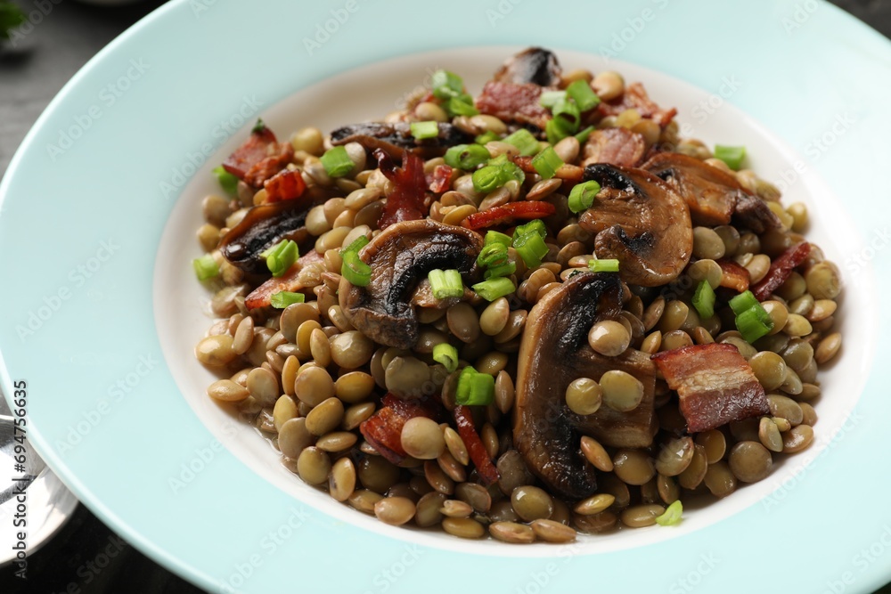 Delicious lentils with mushrooms, bacon and green onion on table, closeup Delicious lentils with mushrooms, bacon and green onion on table, closeup